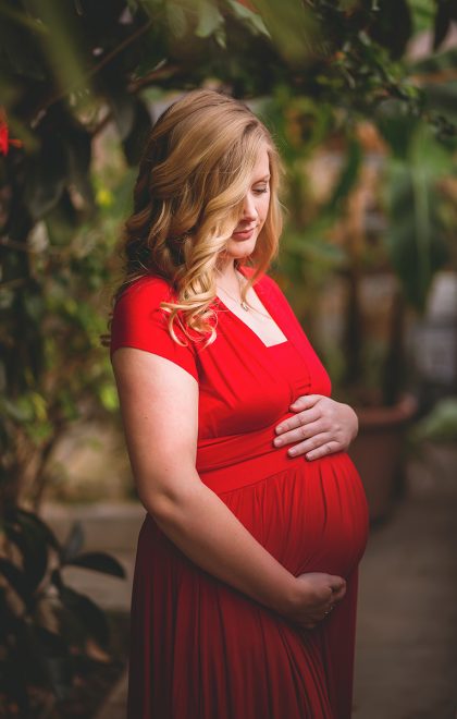 maternity session with red dress in greenhouse