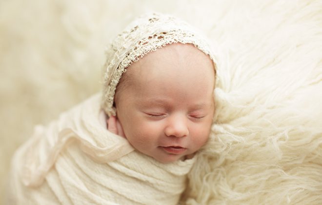 smiling newborn with cream bonnet