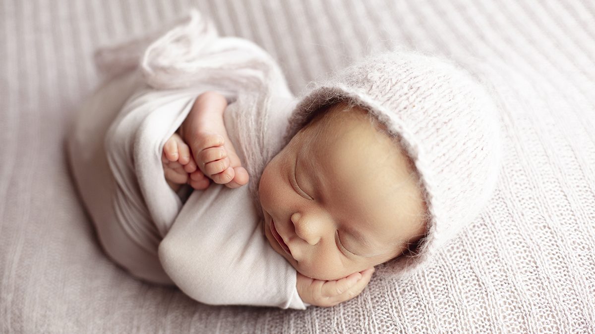 sleepy smiling wrapped newborn