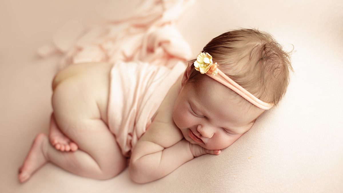 posed newborn photo on soft pink backdrop