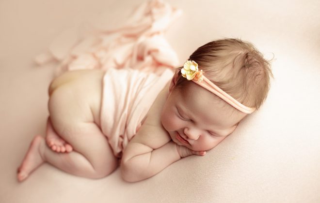 posed newborn photo on soft pink backdrop