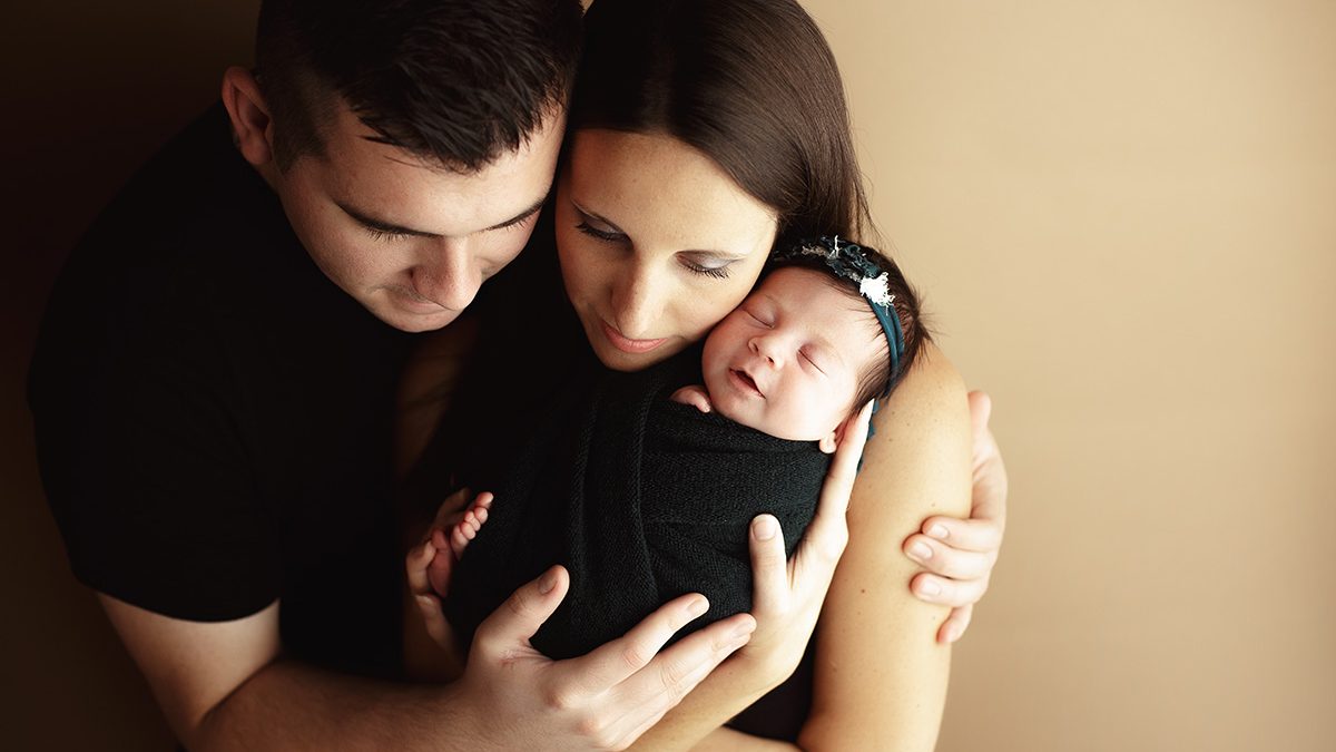 mom and dad snuggling baby during newborn photo session escanaba michigan