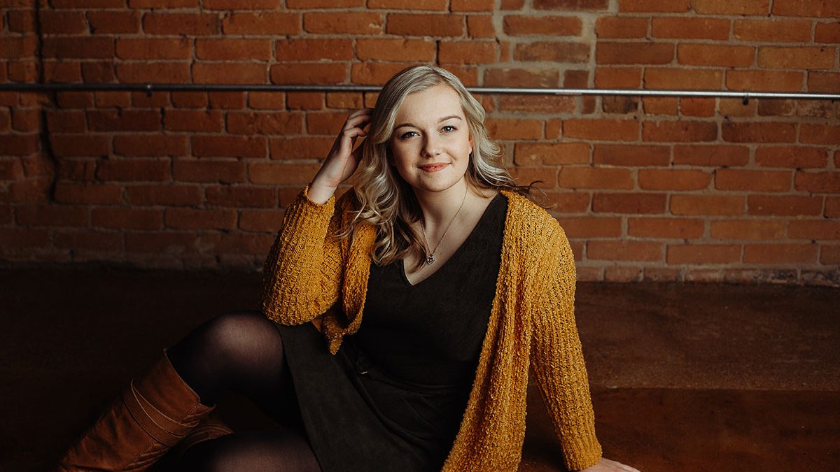 studio senior portrait with brick backdrop