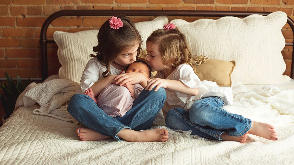 three sisters pose together during baby girl newborn session