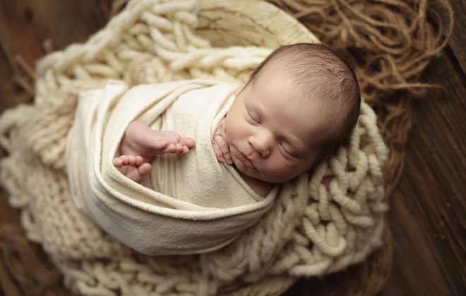 newborn boy posed in bowl with warm neutral props