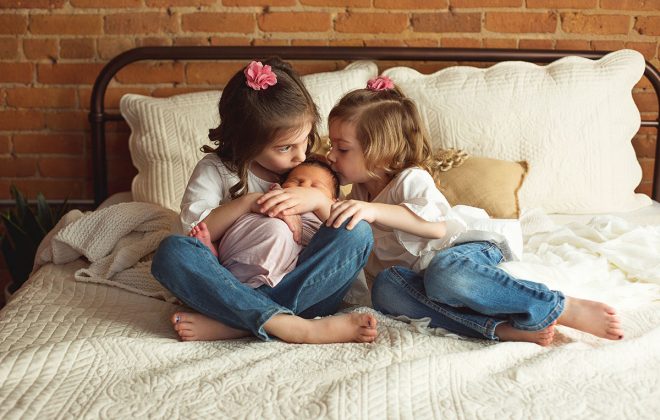 three sisters pose together during baby girl newborn session