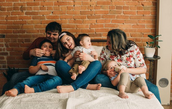 family posed together on bed for studio family photo session in escanaba michigan