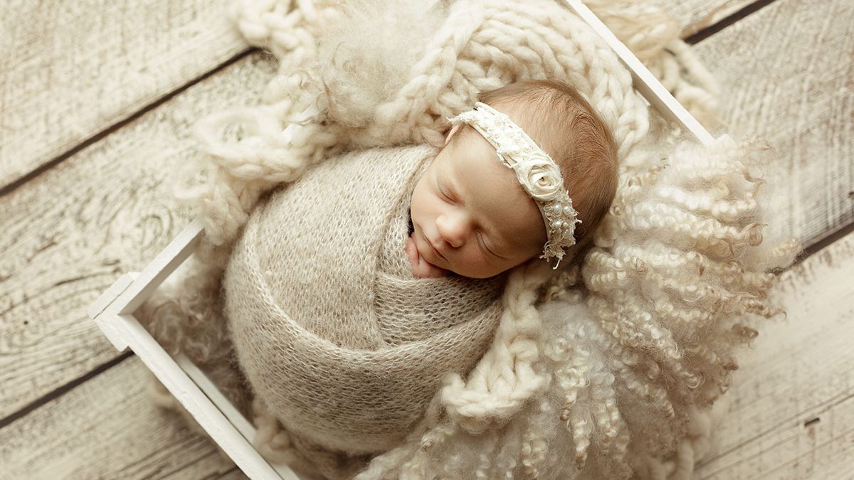 baby girl posed in creamy neutral setup with cream knit brushed alpaca wrap and cream distressed barn wood backdrop in escanaba michigan