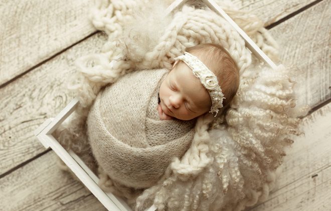 baby girl posed in creamy neutral setup with cream knit brushed alpaca wrap and cream distressed barn wood backdrop in escanaba michigan
