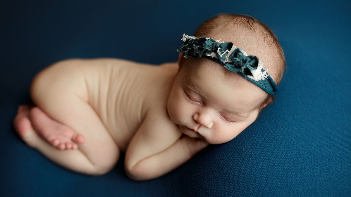 newborn girl posed on teal backdrop during escanaba michigan newborn photo session