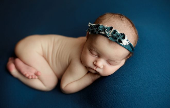 newborn girl posed on teal backdrop during escanaba michigan newborn photo session