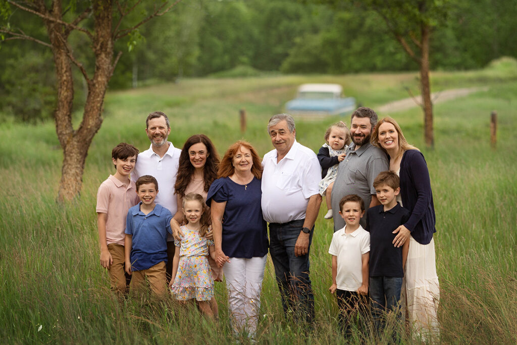 extended family poses together in front of a grassy field with grandpa's vintage Chevrolet truck in the background.